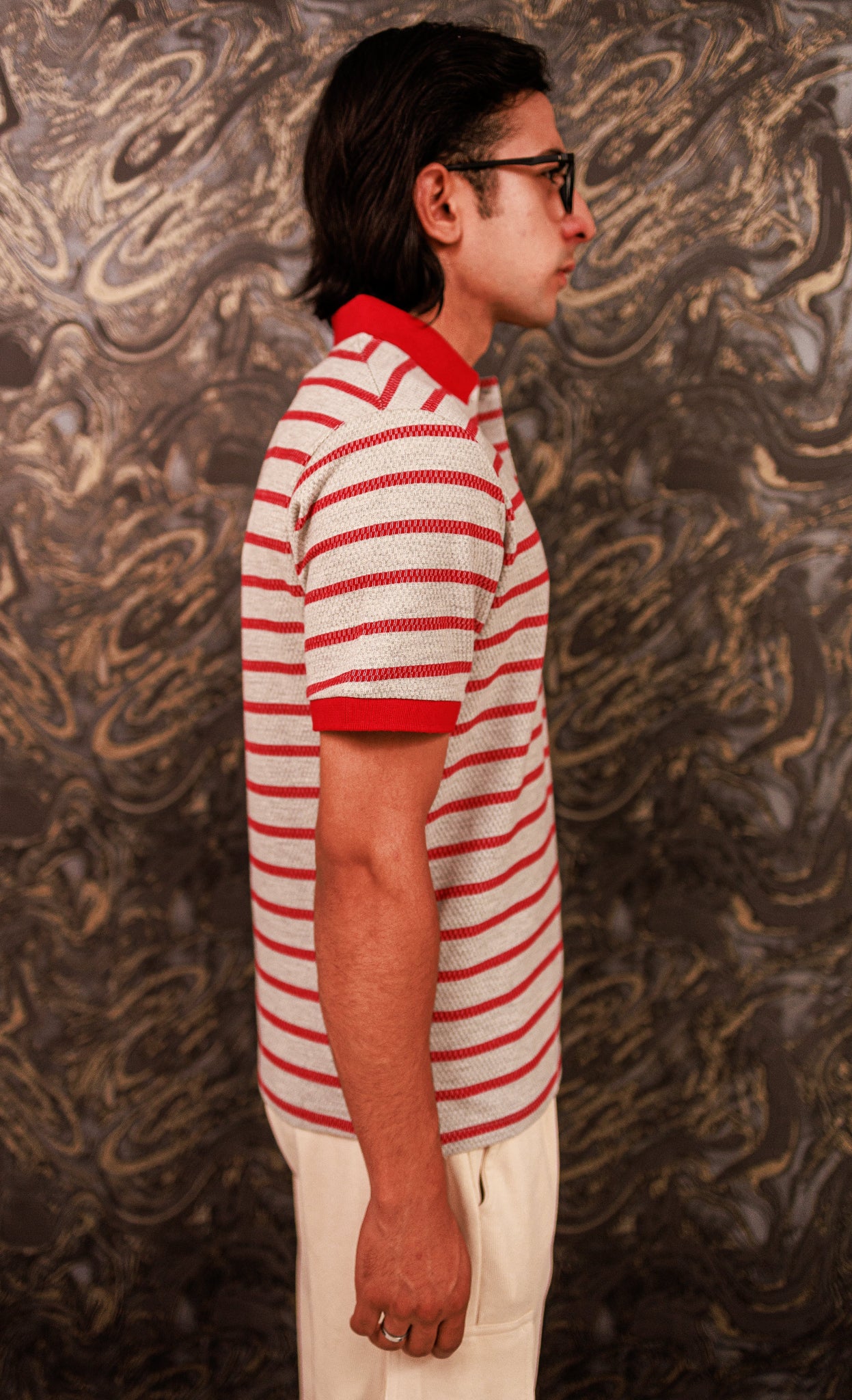 Person wearing a red and white striped shirt against a textured wall.