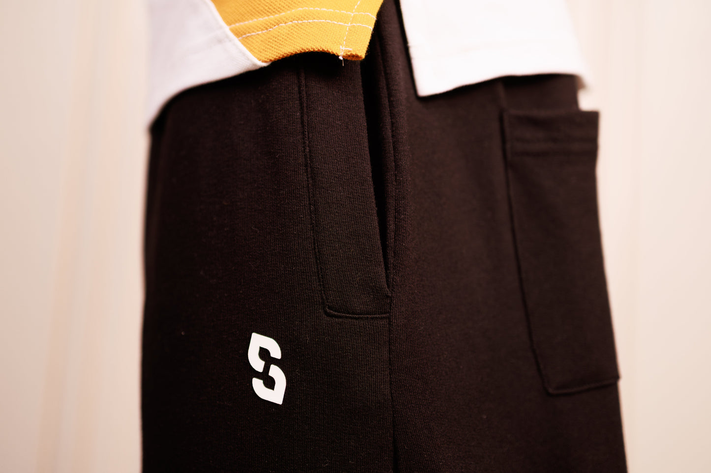 Black pants with a white logo on a beige background