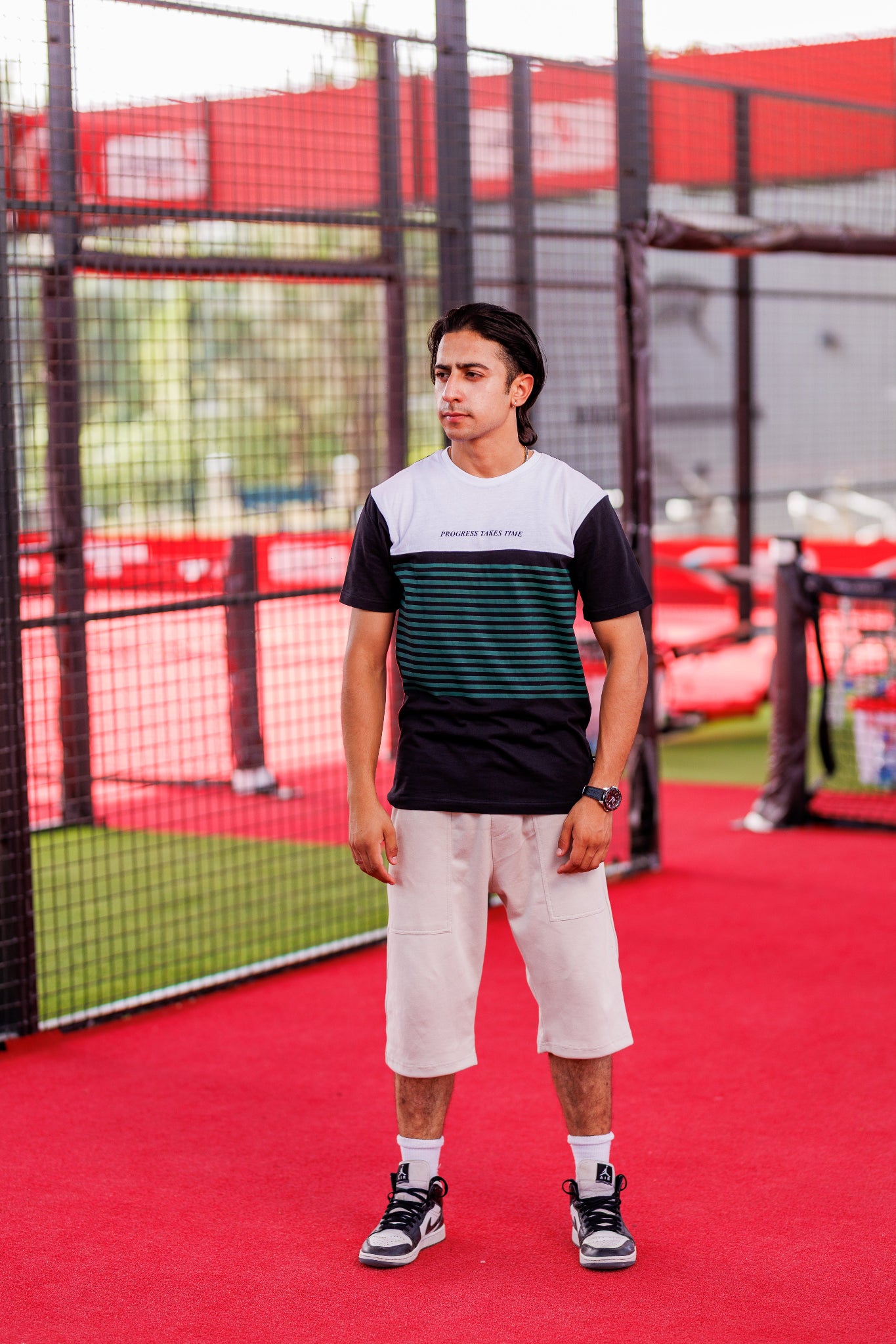 Person standing on a red sports court with a net in the background