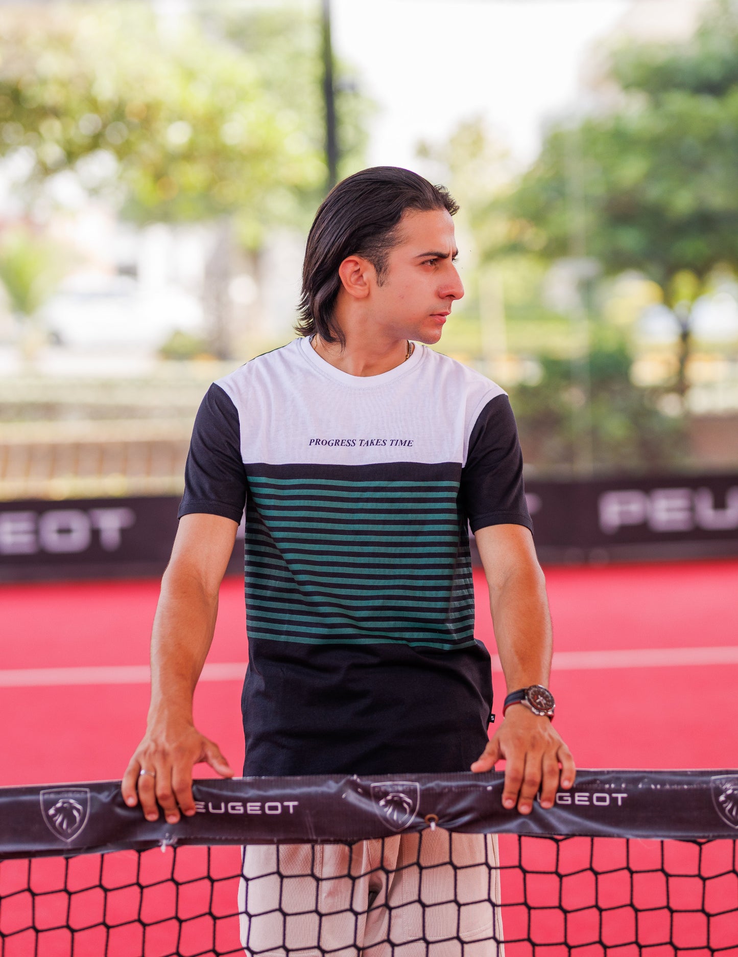 Man standing behind a paddle on a tennis court with a blurred background