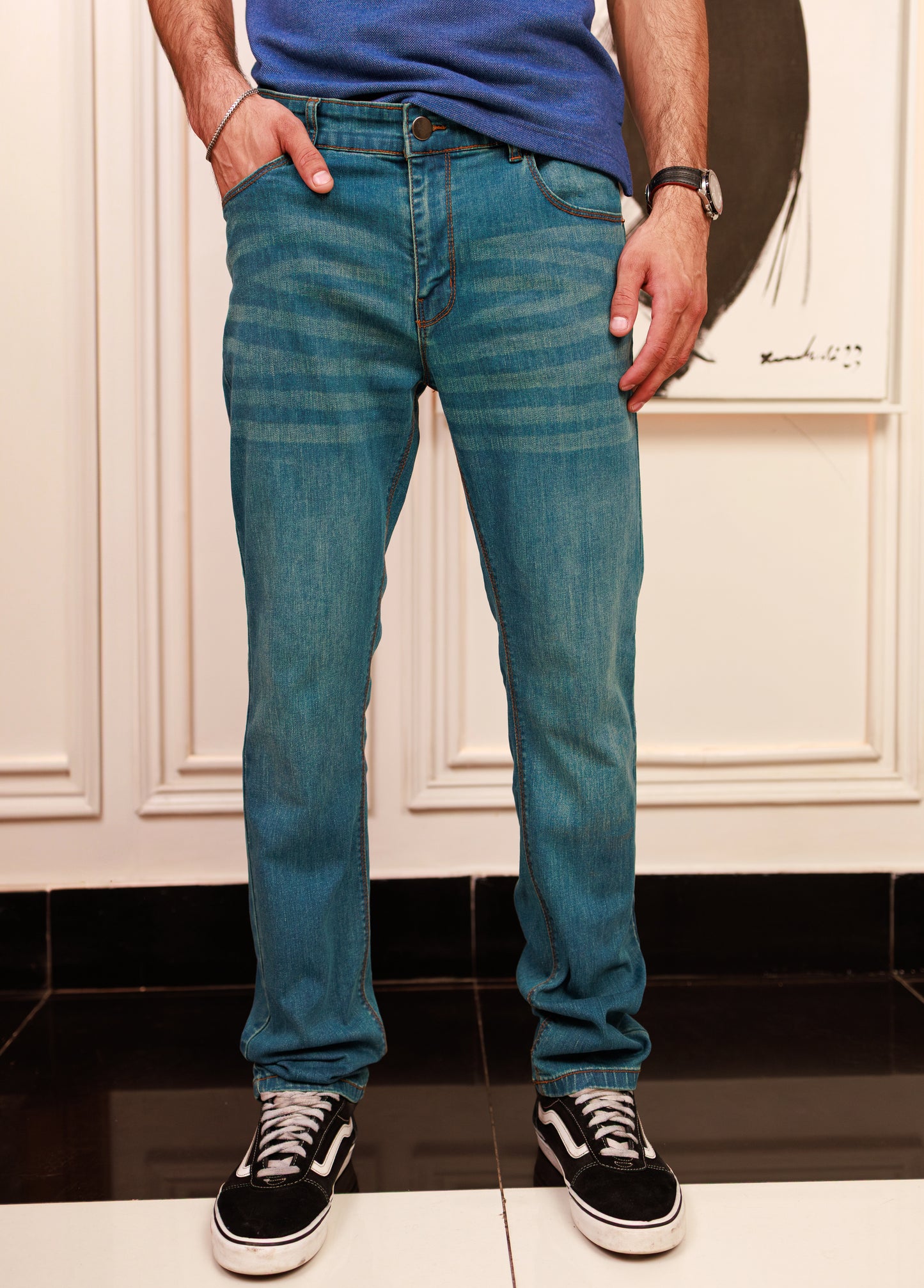 Person wearing blue jeans and white sneakers on a plain background
