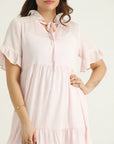 A mid-length pastel pink top with ruffle details and a drawstring neckline.