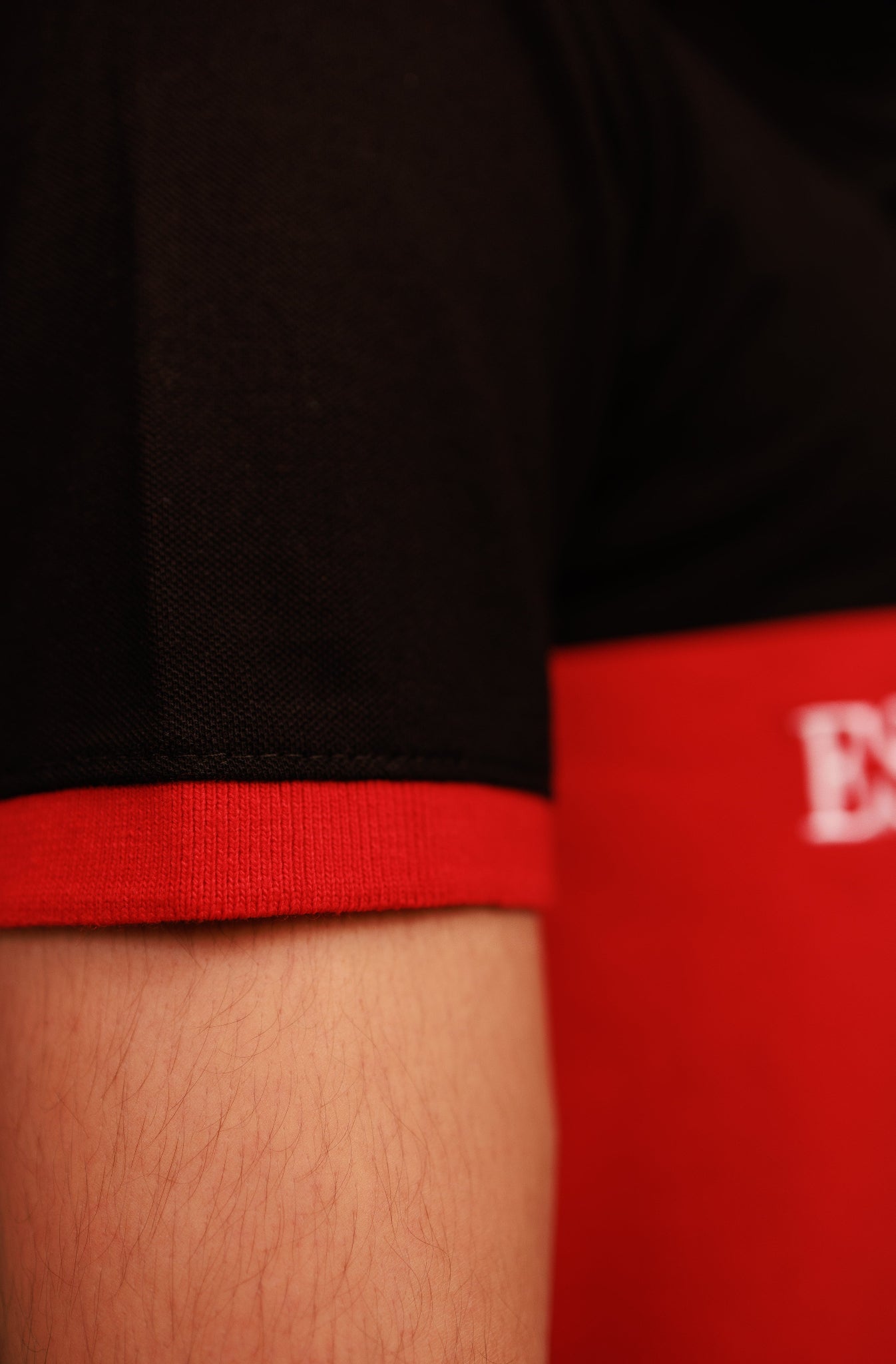 Close-up of a person wearing red underwear with a black shirt and visible brand logo.
