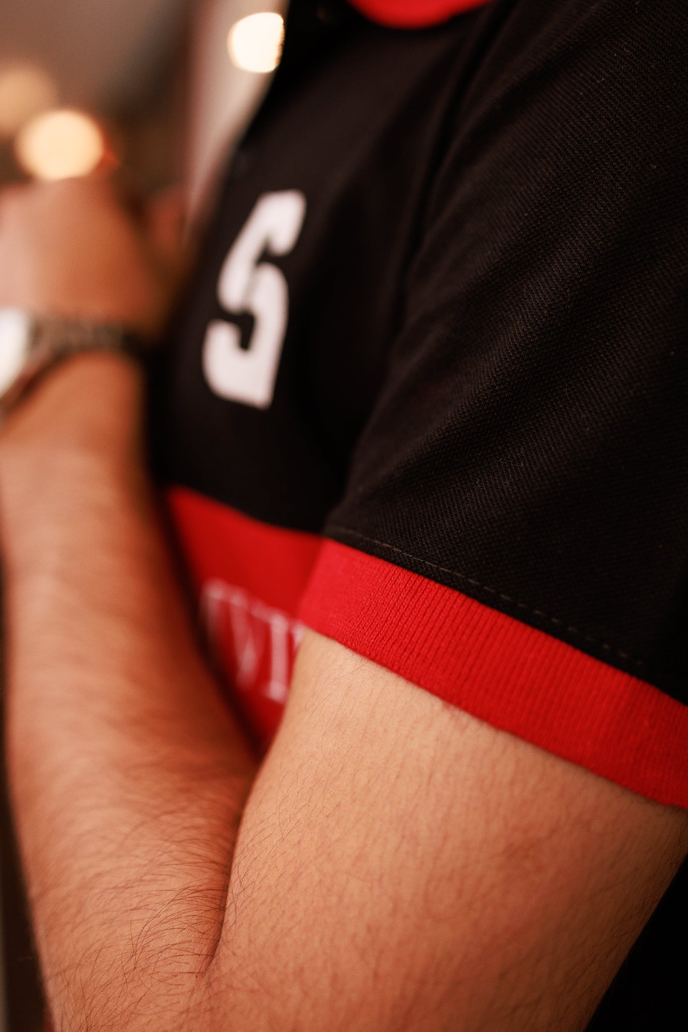 Close-up of a person wearing a black sports jersey with red accents and a visible number '5'.
