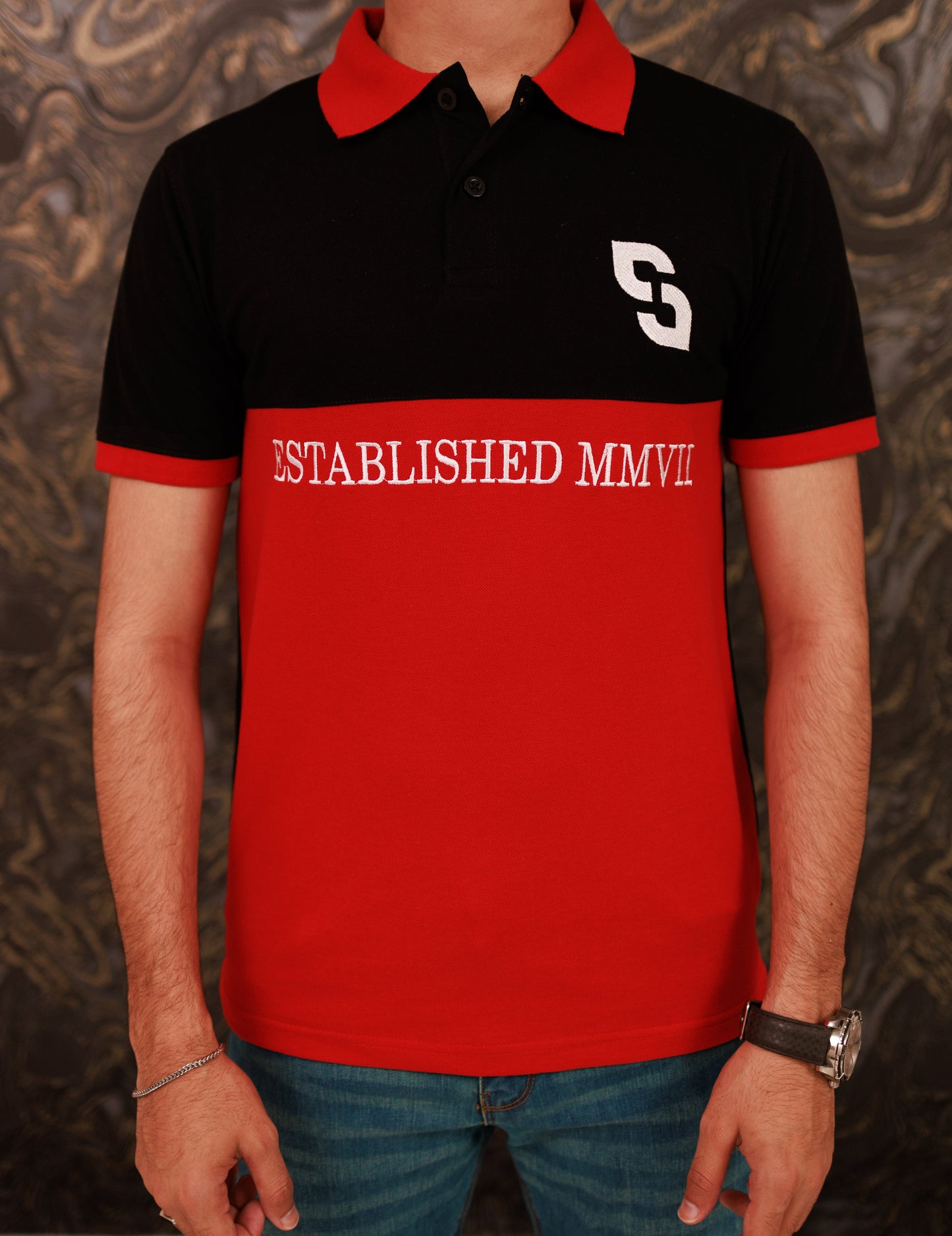 Person wearing a black and red polo shirt with 'S' logo and 'ESTABLISHED MMVII' text.