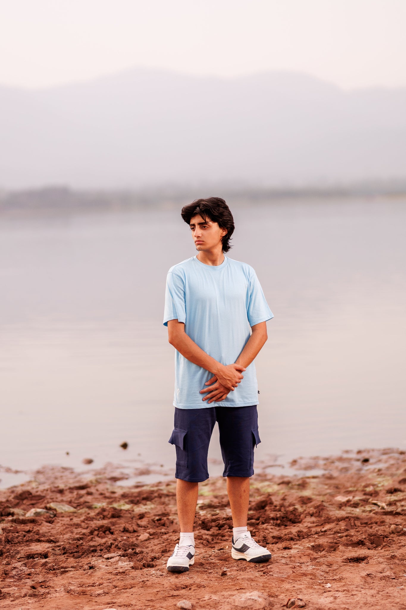 Person standing on a rocky shore with a misty background