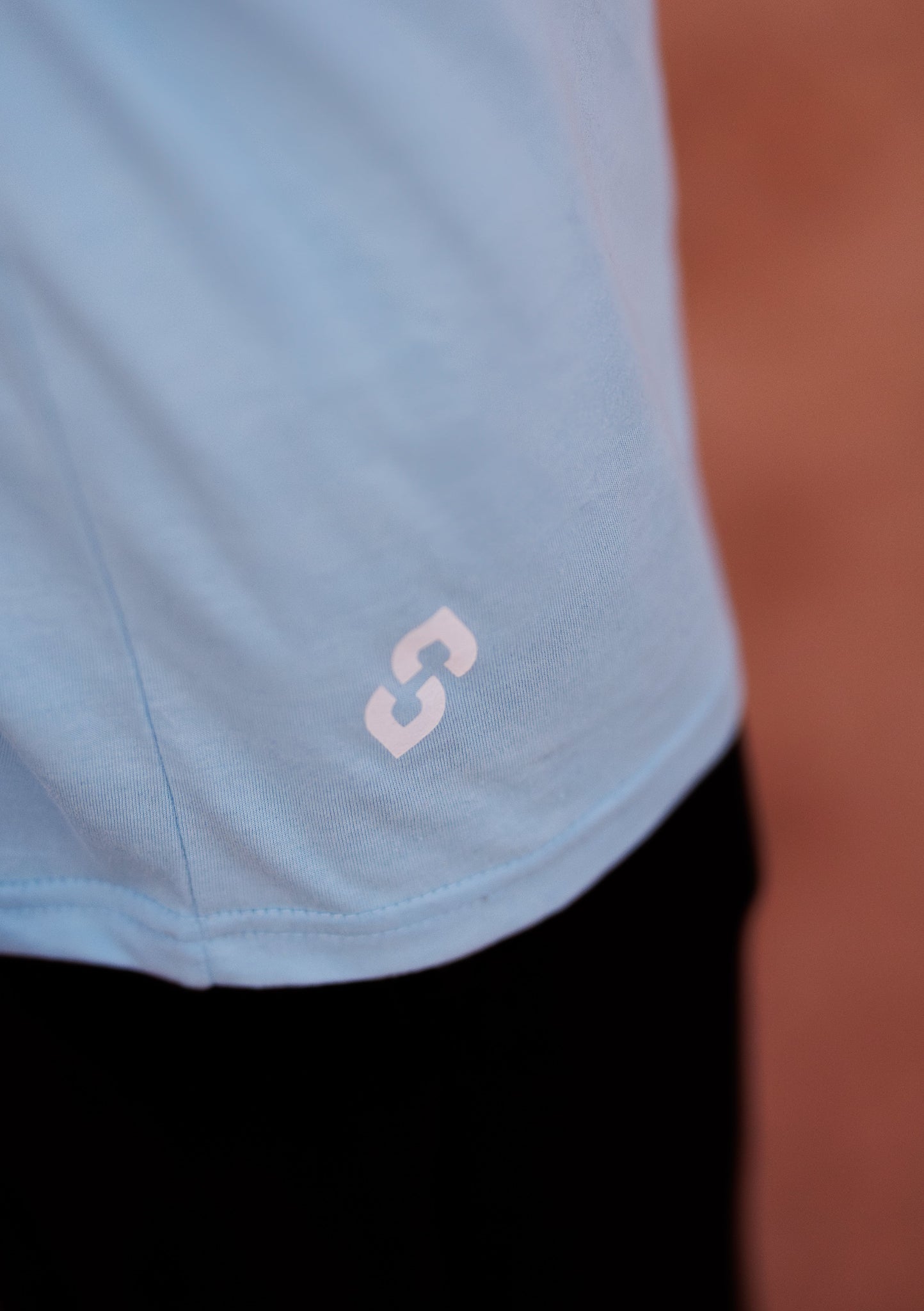 Light blue athletic shirt with a logo on a blurred background