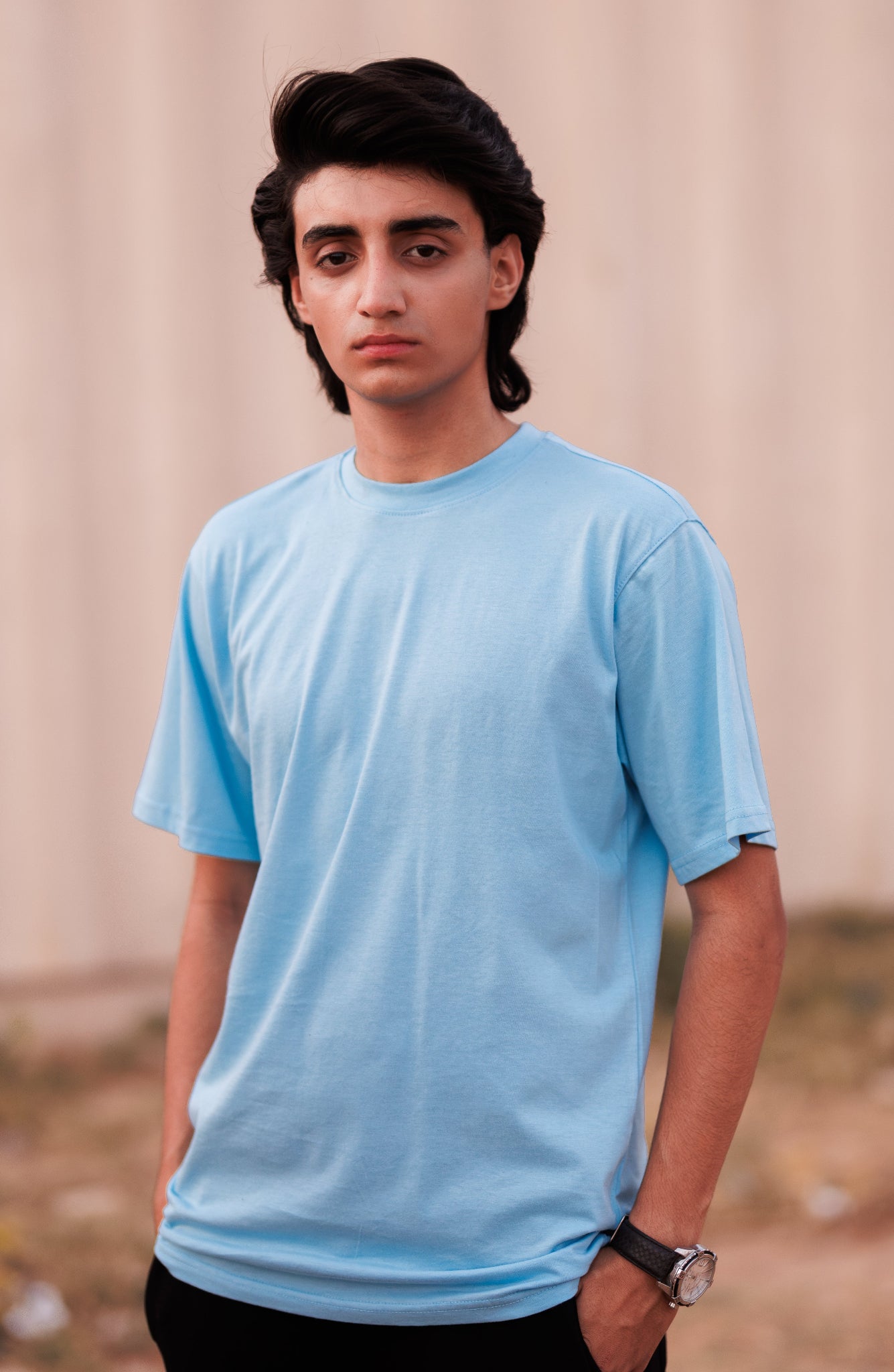 Person wearing a light blue t-shirt against a neutral background