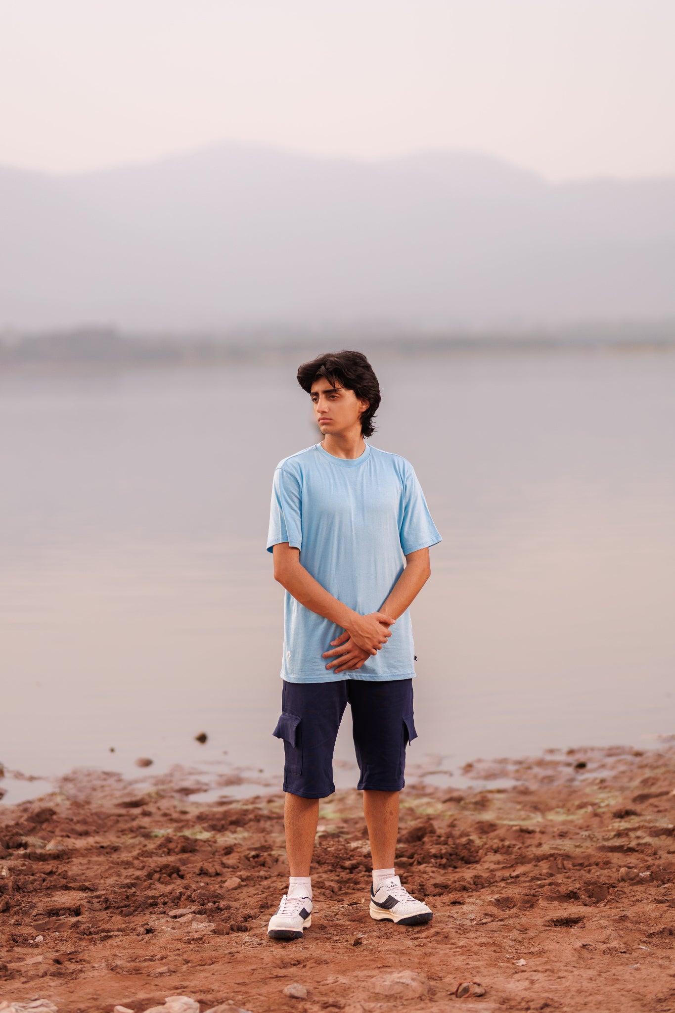 Person standing on a rocky shore with a misty background