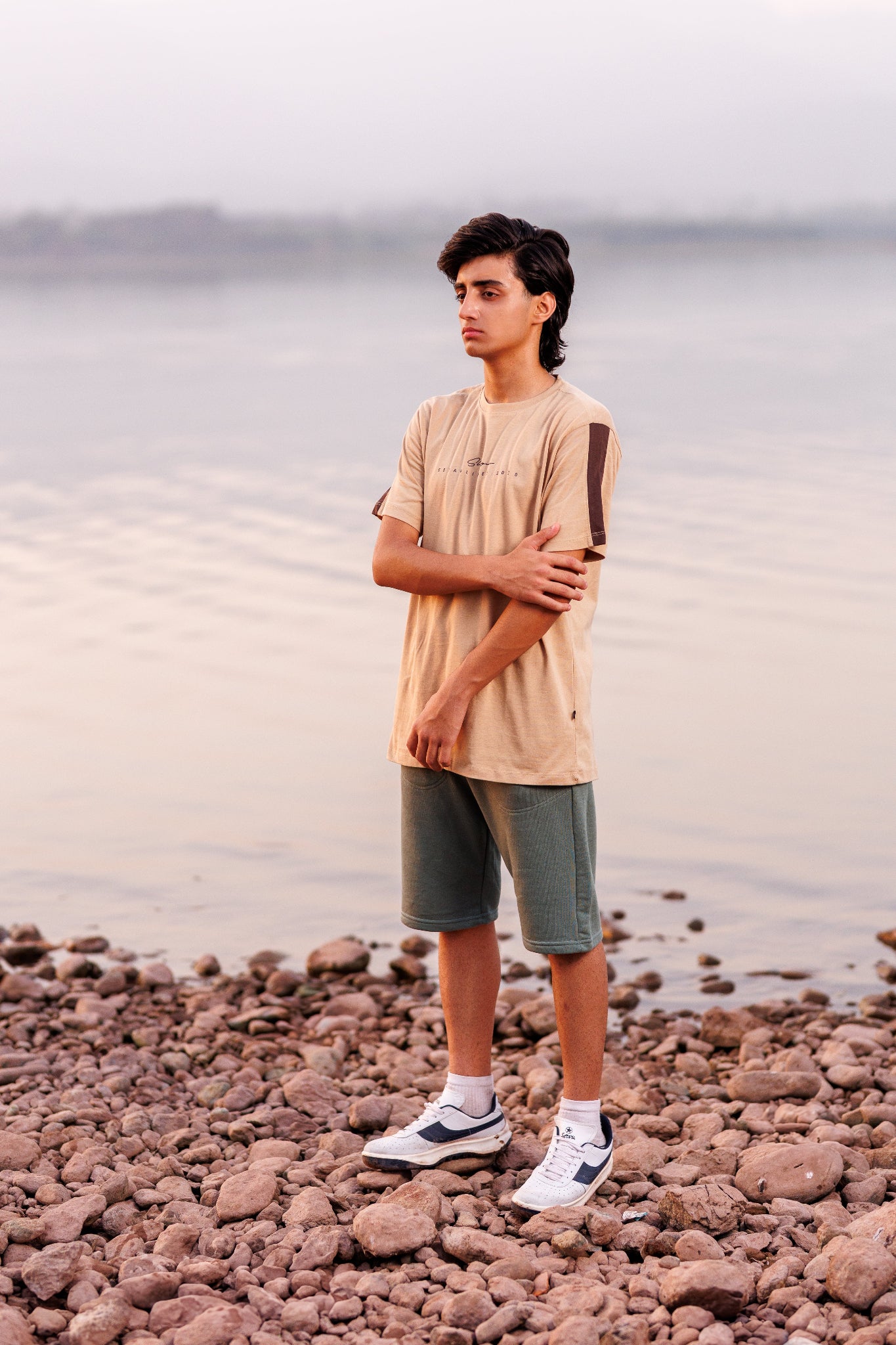 Person standing on a rocky beach with water in the background