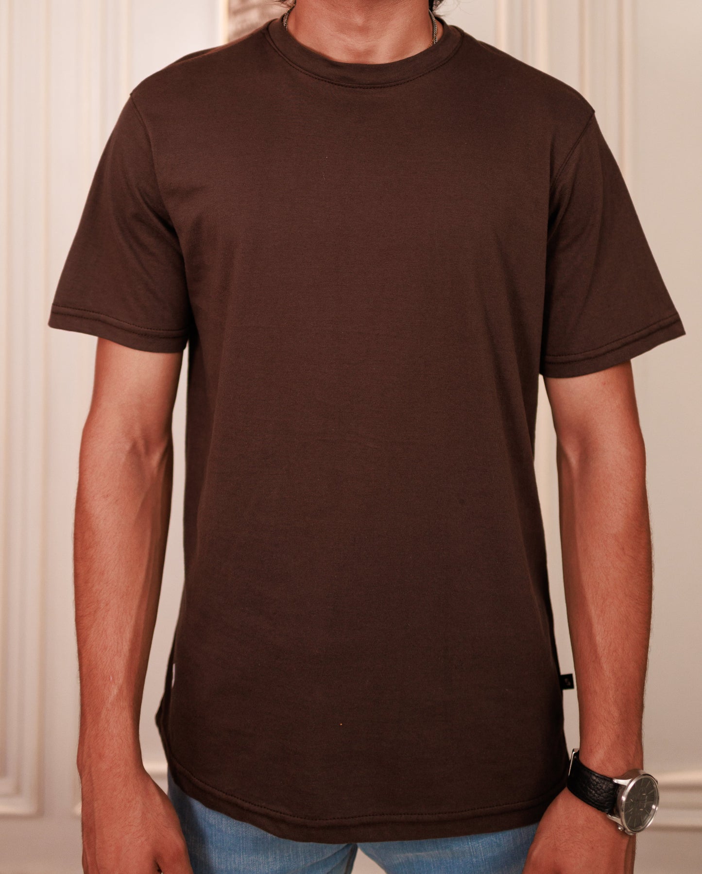 Person wearing a plain brown t-shirt with a neutral background