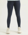 A pair of navy blue leggings on a female model paired with a blue top and white sneakers, standing against a white background.