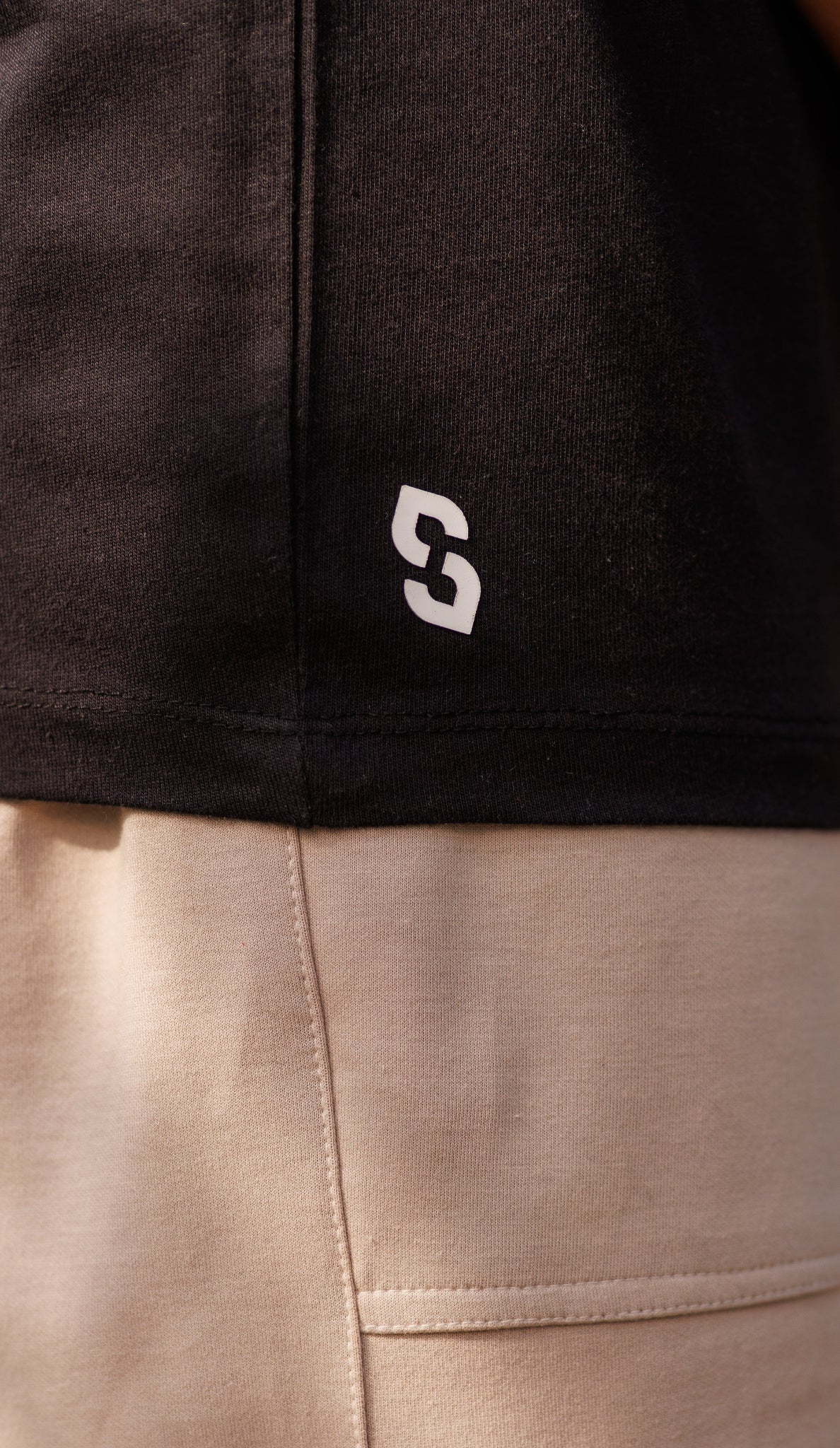 Close-up of a black and beige garment with a logo on the black section.