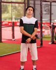 Person standing on a red sports court wearing a black and white striped shirt and beige shorts.