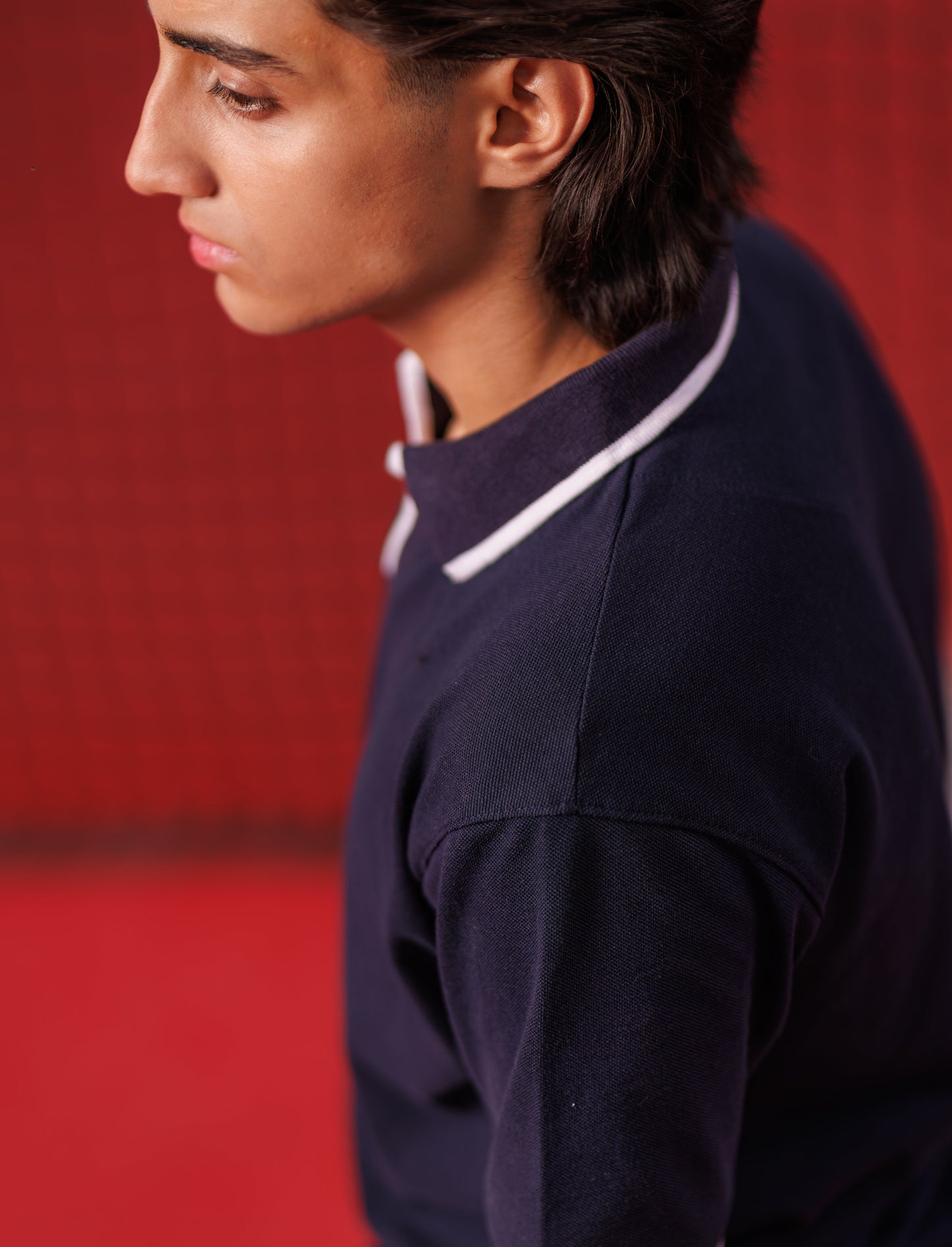 Person wearing a dark blue outfit with white trim against a red background
