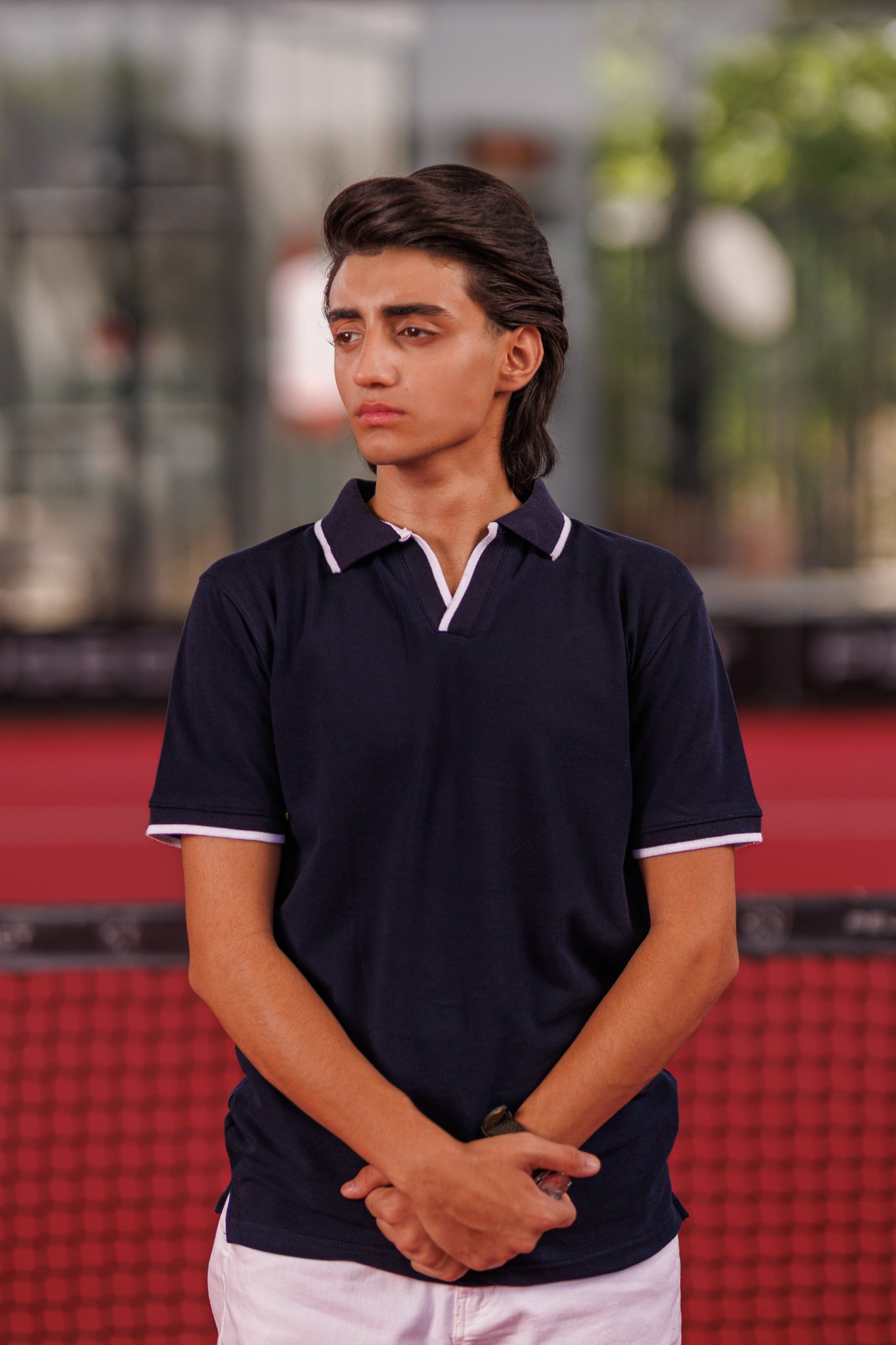 Person wearing a navy blue polo shirt with white trim on a blurred background