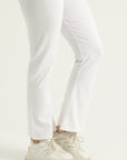 White pants worn with white sneakers on a light gray background