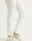 White pants worn with white sneakers on a light gray background