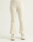 A pair of beige flared leggings with a high waistband, worn with white sneakers.