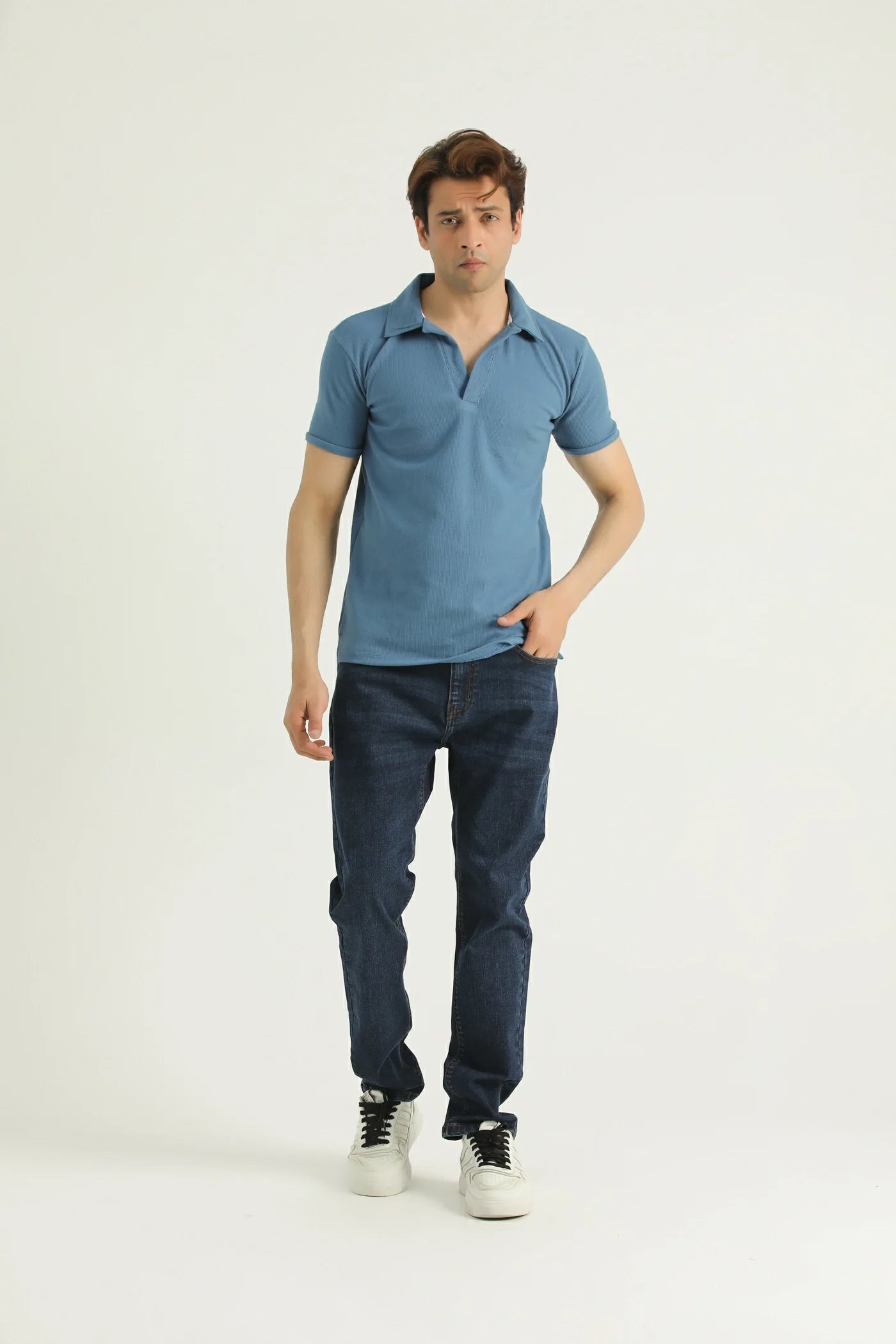 A man wearing a blue short-sleeved polo shirt with a collar, and blue jeans.