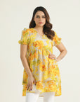A mid-length floral-printed tunic in marigold yellow with orange and white flowers, featuring a V-neckline, short elasticated sleeves, and a double-tiered hemline.