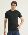 A man wearing a black short-sleeved round-neck T-shirt and blue jeans.