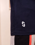 Navy shorts with a logo on the corner, beige and black pants with red stripe in the background