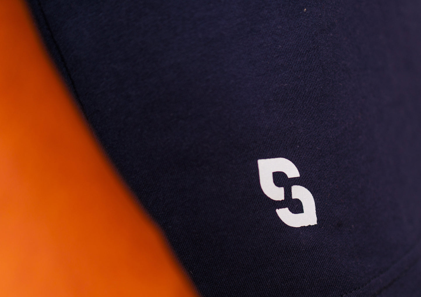 Close-up of a black shirt with a white logo on an orange background