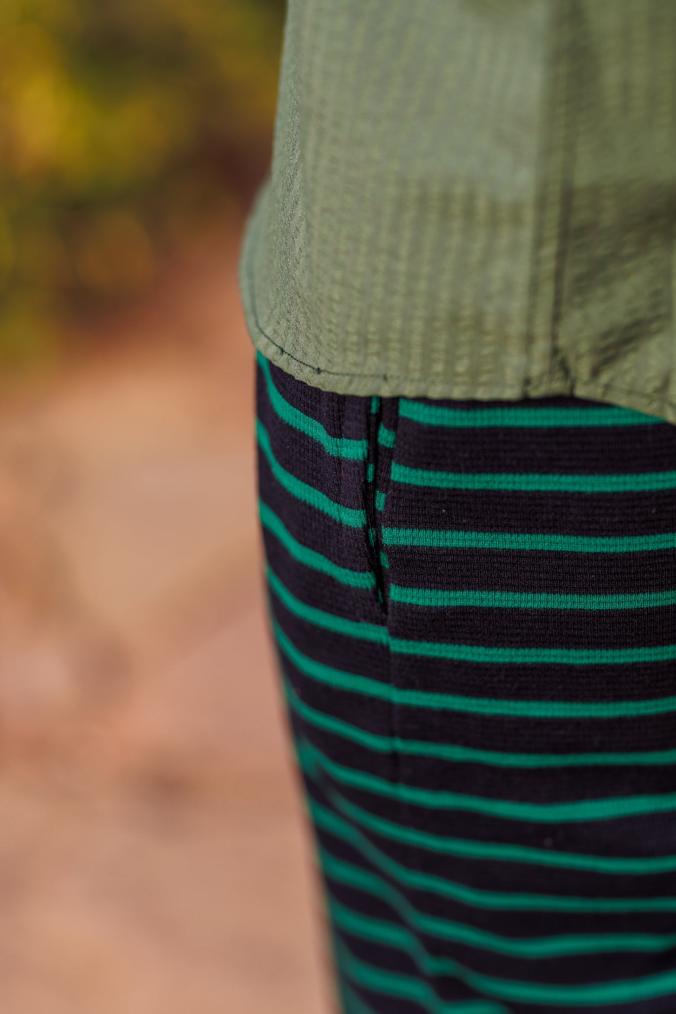 Close-up of green and black striped fabric with a blurred natural background