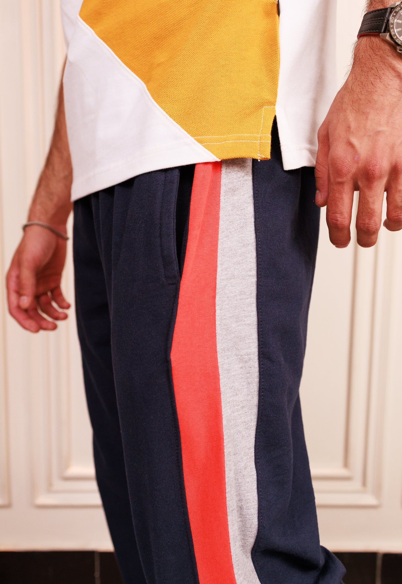 Colorful pants with a white top worn by a person, against a neutral background