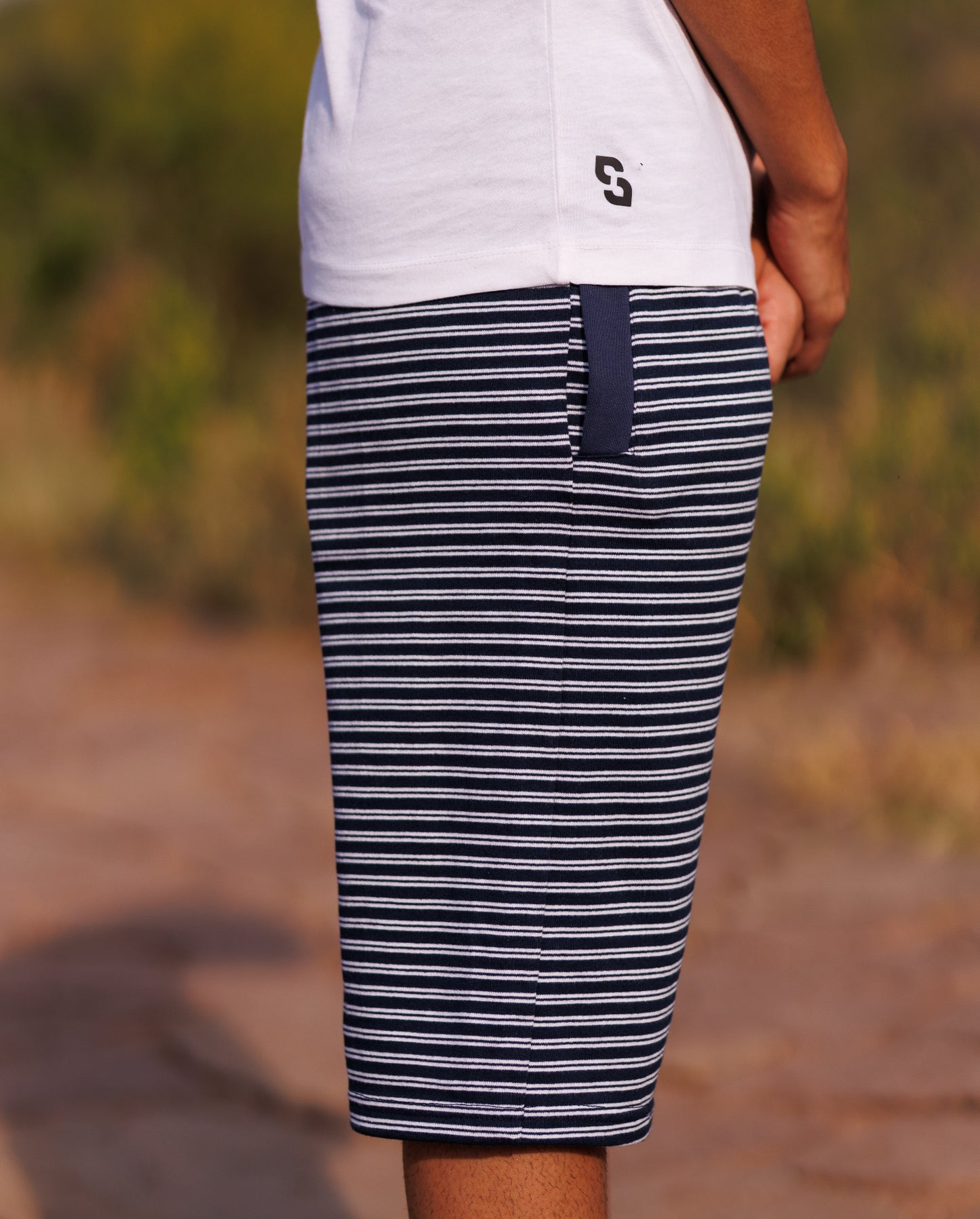 Person wearing navy and white striped shorts with a blurred outdoor background