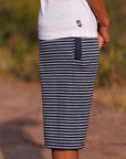 Person wearing navy and white striped shorts with a blurred outdoor background