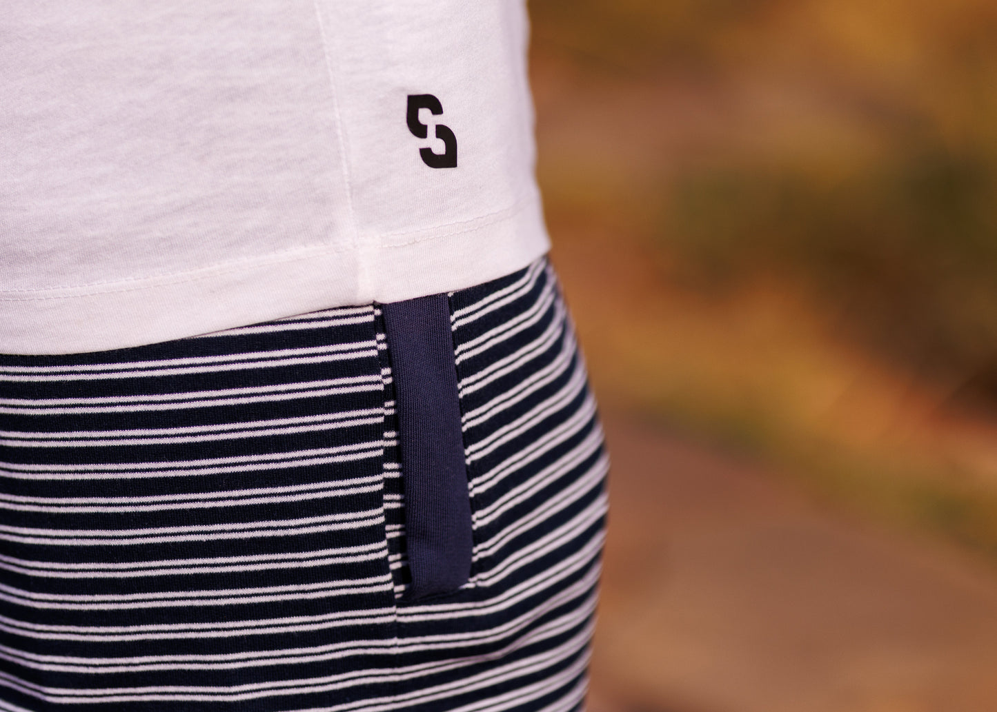 Close-up of a person wearing a white shirt with a logo and a black and white striped apron.