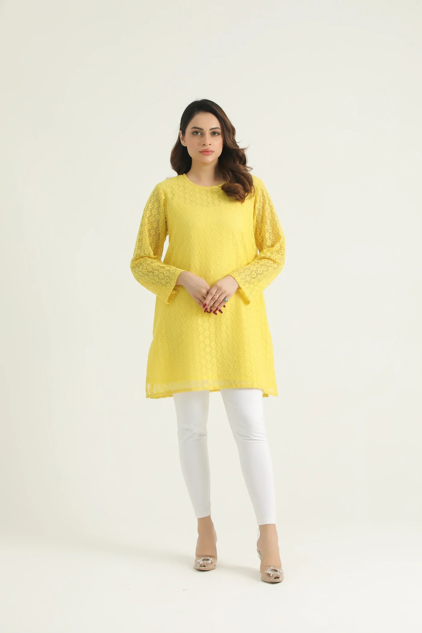 A woman wearing a mustard yellow chikenkari top with long straight sleeves and a round neck. The top has a back opening and under lining attached.