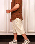 Person wearing a brown shirt, beige shorts, and gray Nike sneakers in a kitchen.