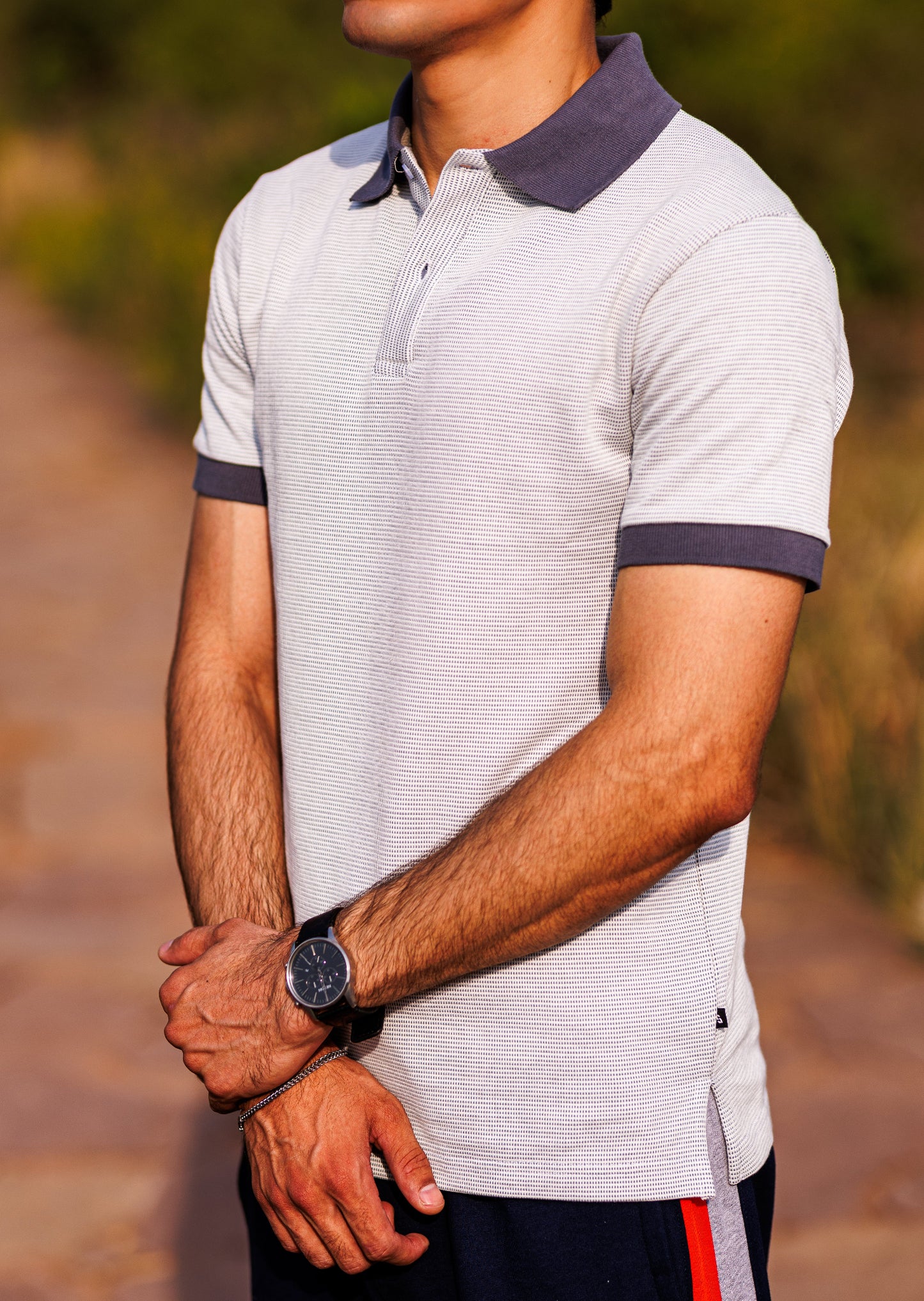 Man wearing a patterned polo shirt with a blurred natural background