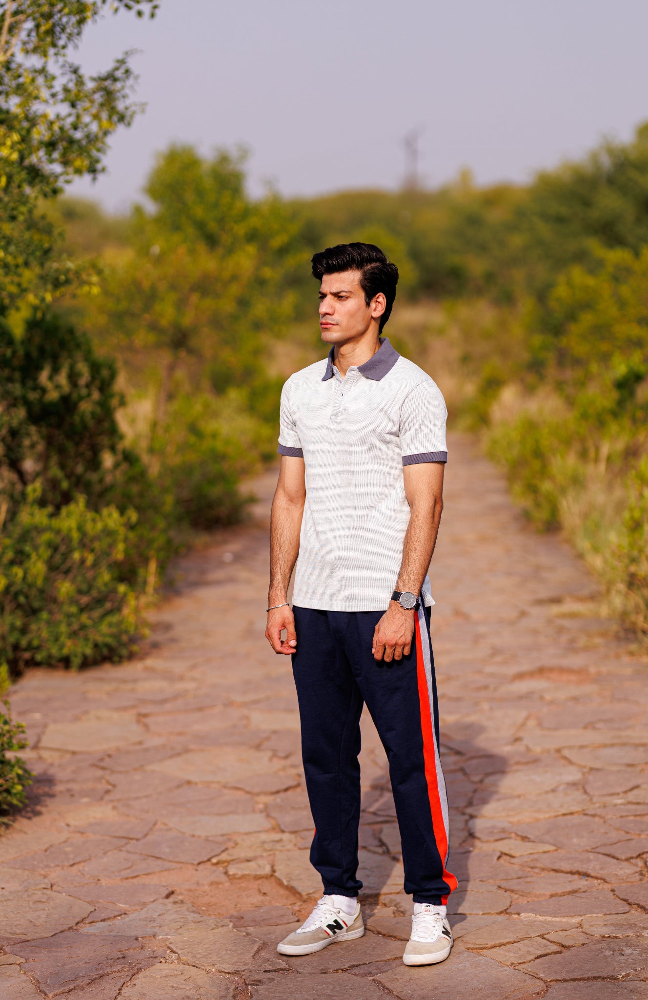 Man standing on a stone path with greenery in the background