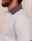 Man wearing a gray and white striped polo shirt with a collar.