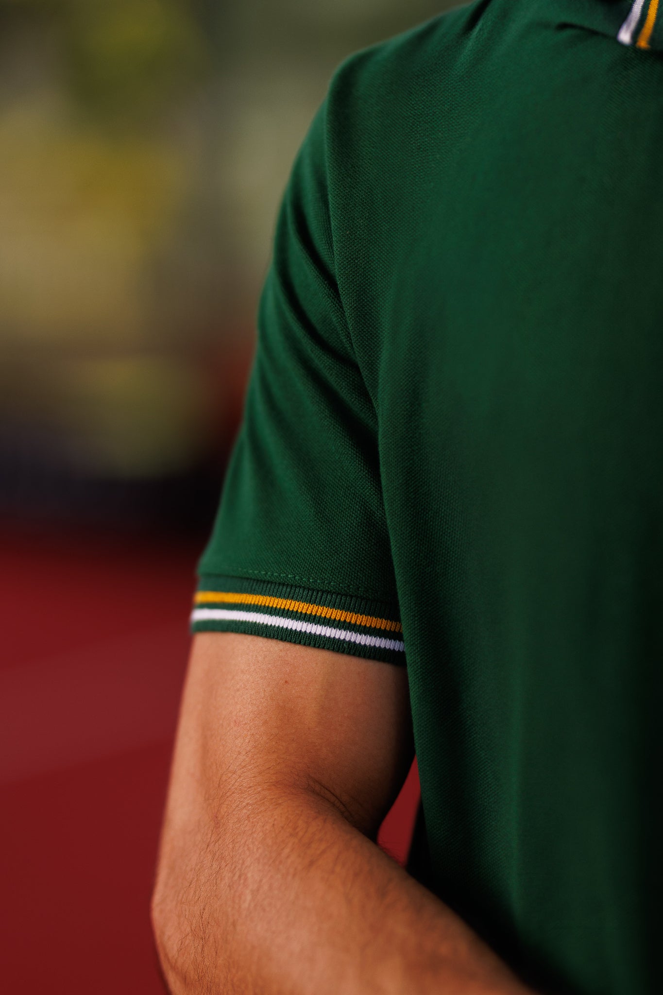 Green polo shirt with striped cuffs on a blurred background