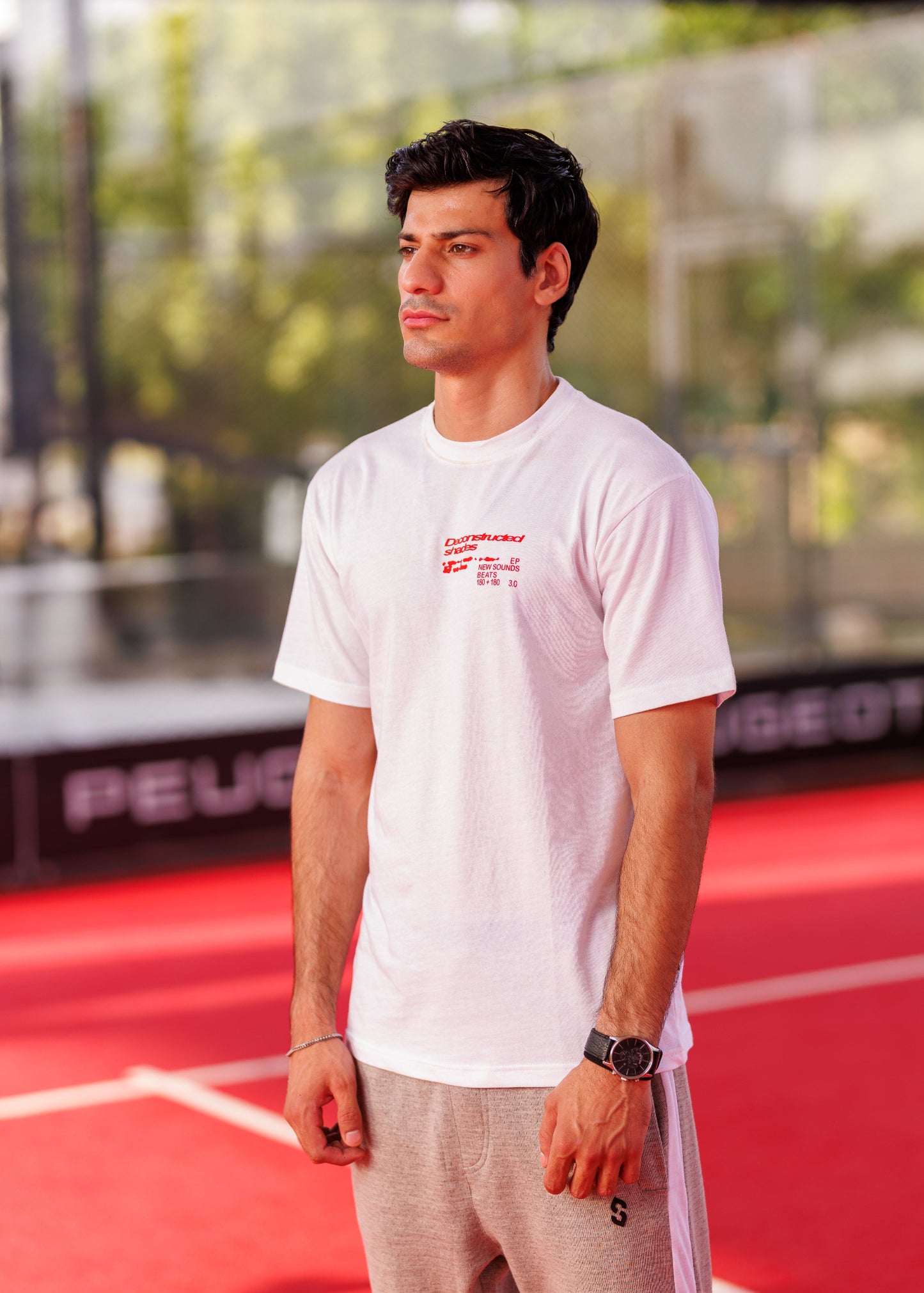 Man wearing a white t-shirt with red text on a sports court