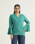 A woman wearing a turquoise green top with a round neckline and long flared sleeves. The top is a knit fabric and the image shows the top in a vertical orientation.