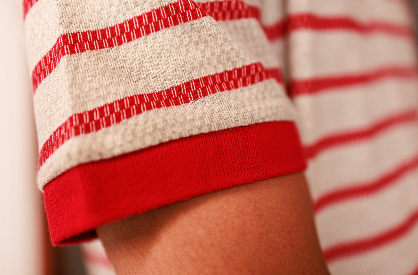 Close-up of a person wearing a red and white striped shirt with rolled-up sleeves.