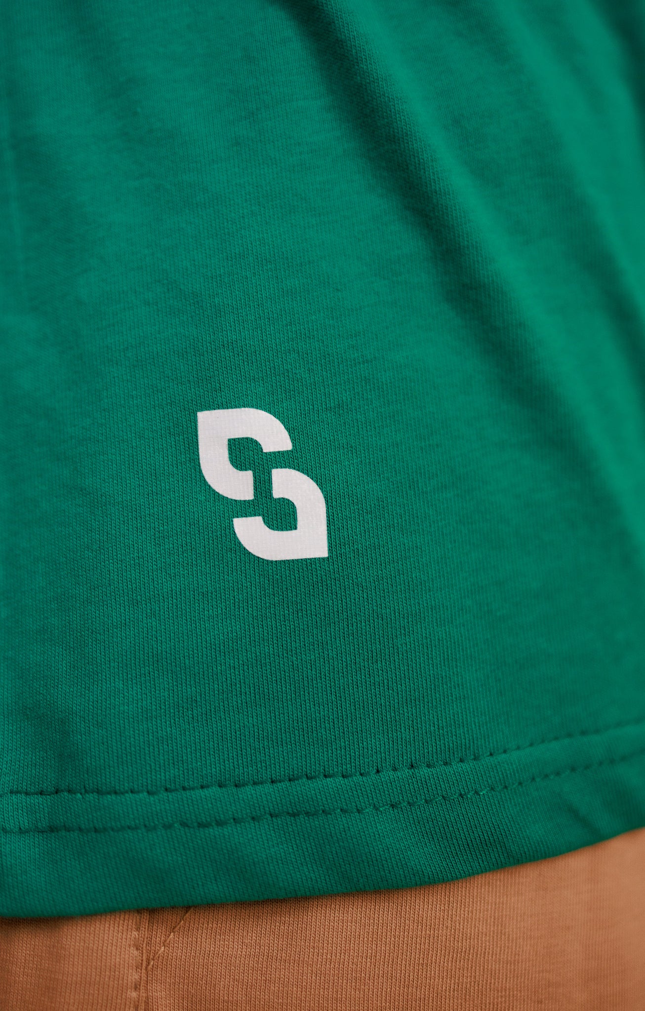 Close-up of a green garment with a white logo on a brown background