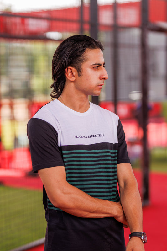 Man wearing a black and white t-shirt with text, standing on a sports field.