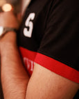 Close-up of a person wearing a black sports jersey with red accents and a visible number '5'.