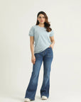A woman wearing a pastel blue knit top with a round neck, raglan sleeves, and elasticated half sleeves, paired with blue jeans.