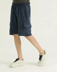 A man wearing navy mid-length cargo knit shorts with an elasticated waistband and white sneakers.