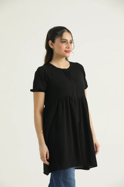A model wearing a mid-length dark saddle top with short sleeves and a round neckline, made of georgette weave fabric.