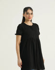 A model wearing a mid-length dark saddle top with short sleeves and a round neckline, made of georgette weave fabric.
