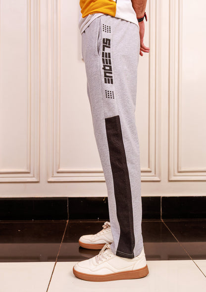 Person wearing gray jogger pants with black accents and white sneakers in a room.